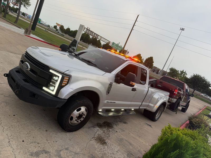 A white towing truck from Turbo Tows assisting a disabled vehicle on the roadside in Houston, Texas.