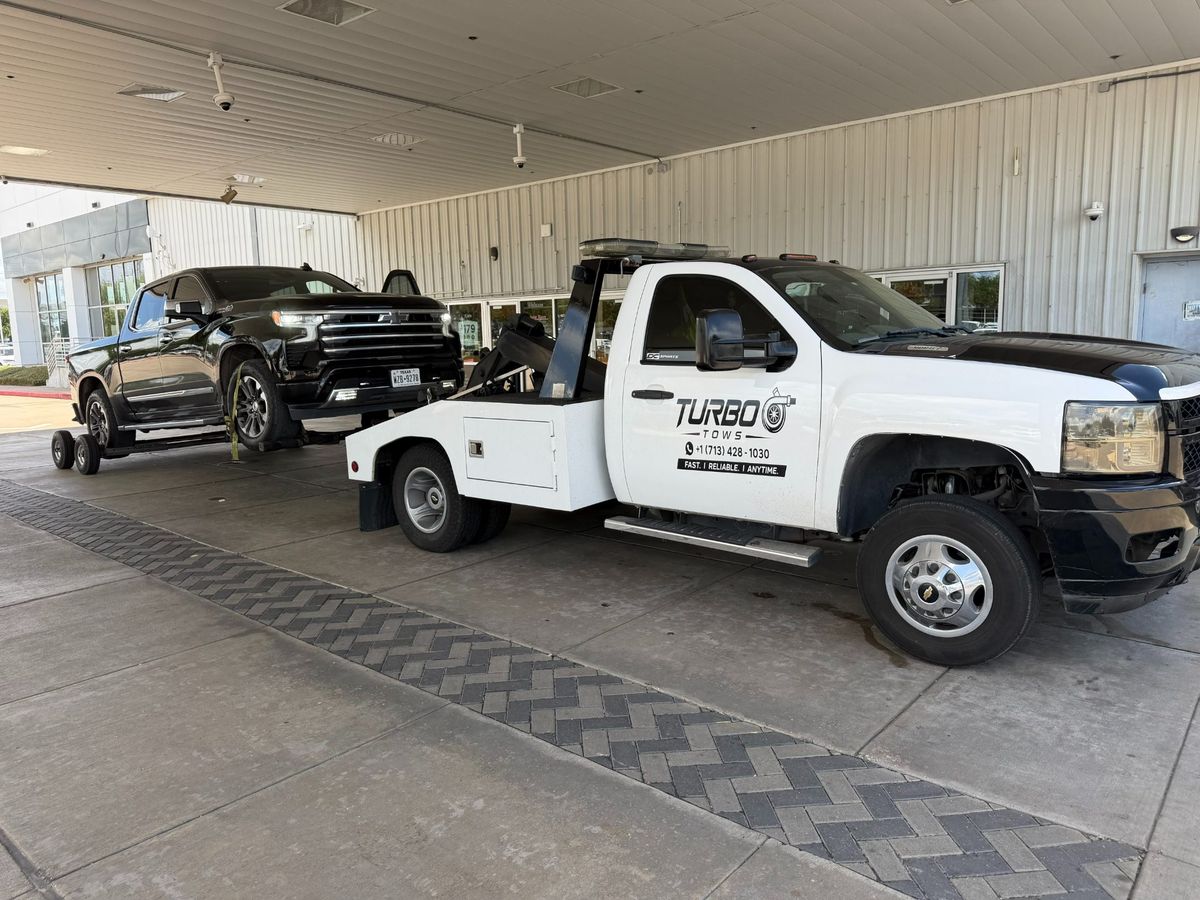 Turbo Tows truck towing a black pickup in Houston, showcasing roadside assistance services.