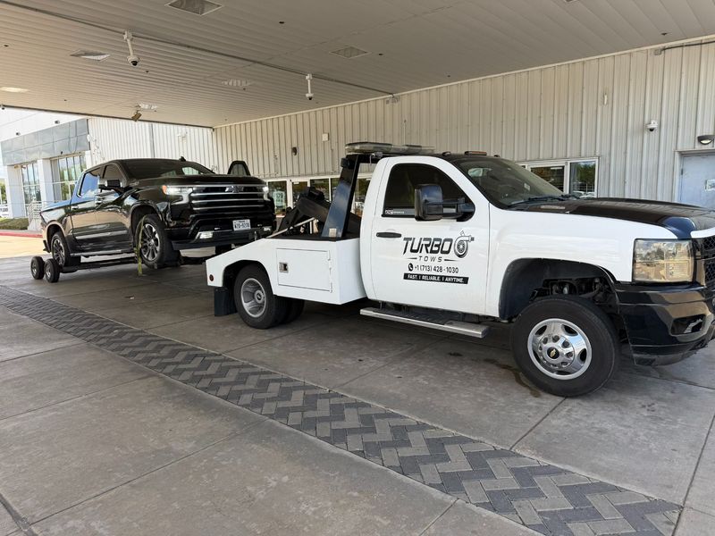 Turbo Tows truck towing a black pickup in Houston, showcasing roadside assistance services.