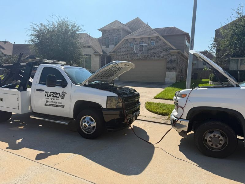 Turbo Tows truck assisting with a jump start service for a vehicle in Houston.