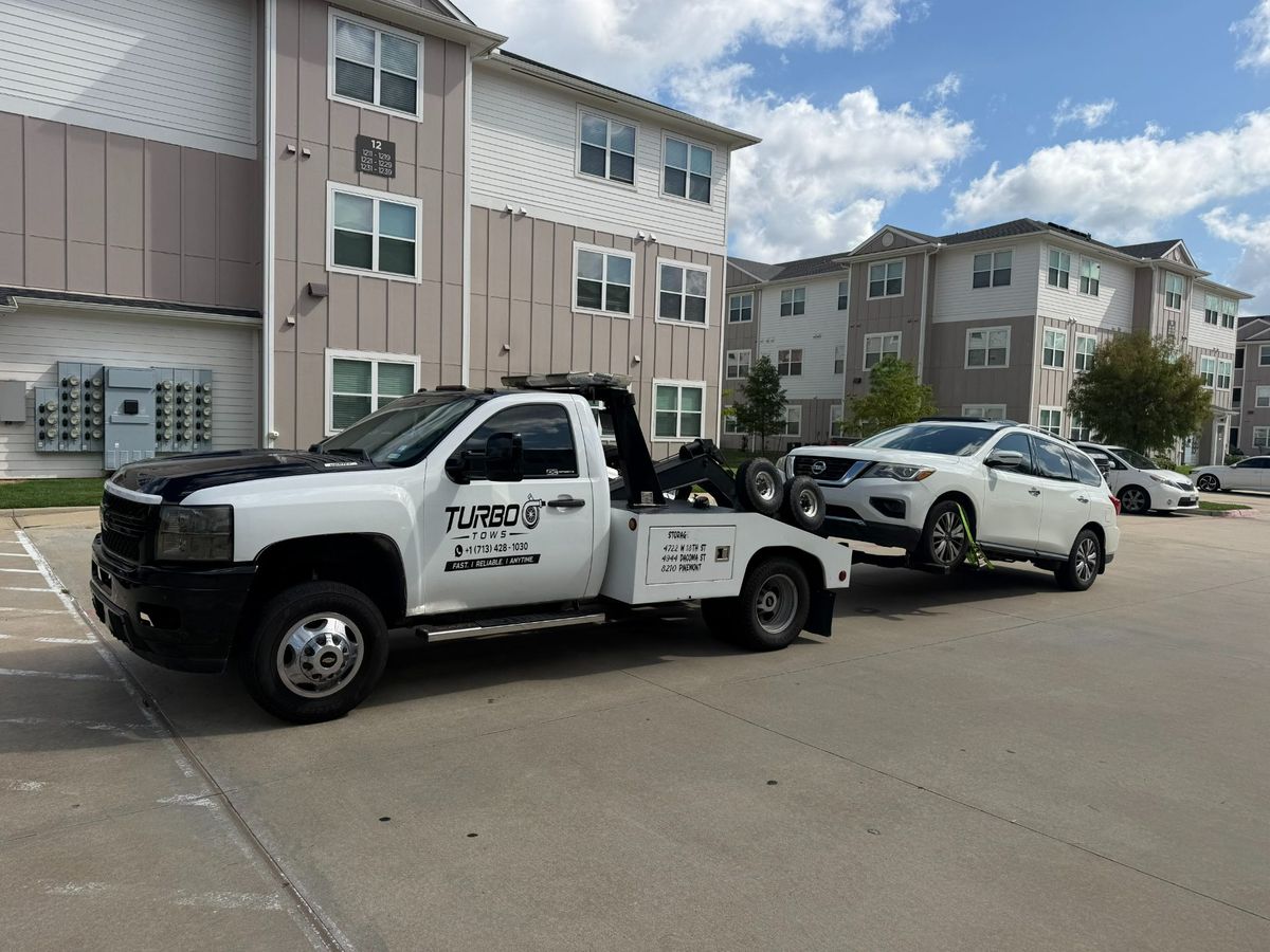 Turbo Tows truck towing a vehicle in a residential area, showcasing roadside assistance services at a cheap price.