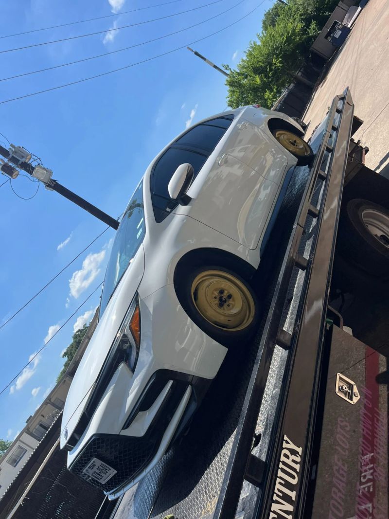 A white car being loaded onto a tow truck in clear blue skies, indicating towing services.