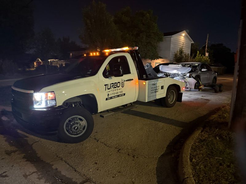 A tow truck from Turbo Tows towing a vehicle at night in Houston after an accident.