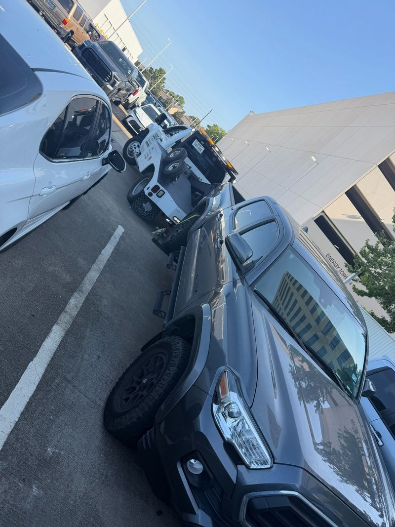 A towing vehicle from Turbo Tows assisting in a parking lot with multiple cars visible.