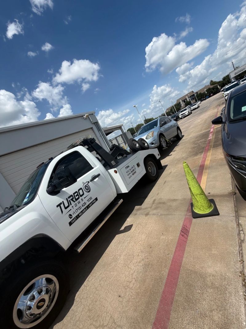 A towing truck from Turbo Tows parked in a lot, showcasing vehicle assistance services in Houston.
