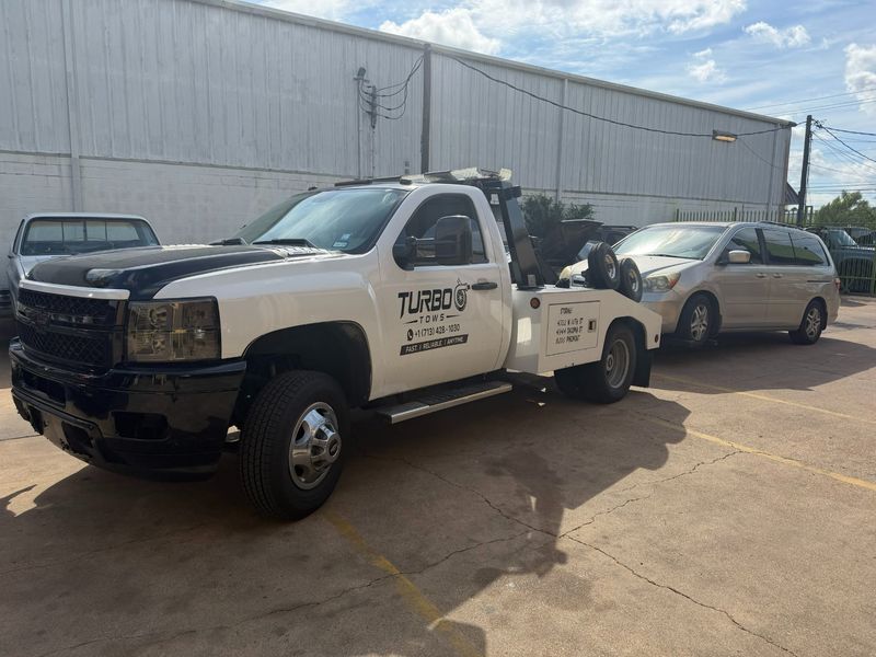 Turbo Tows truck providing towing service for a minivan in Houston.