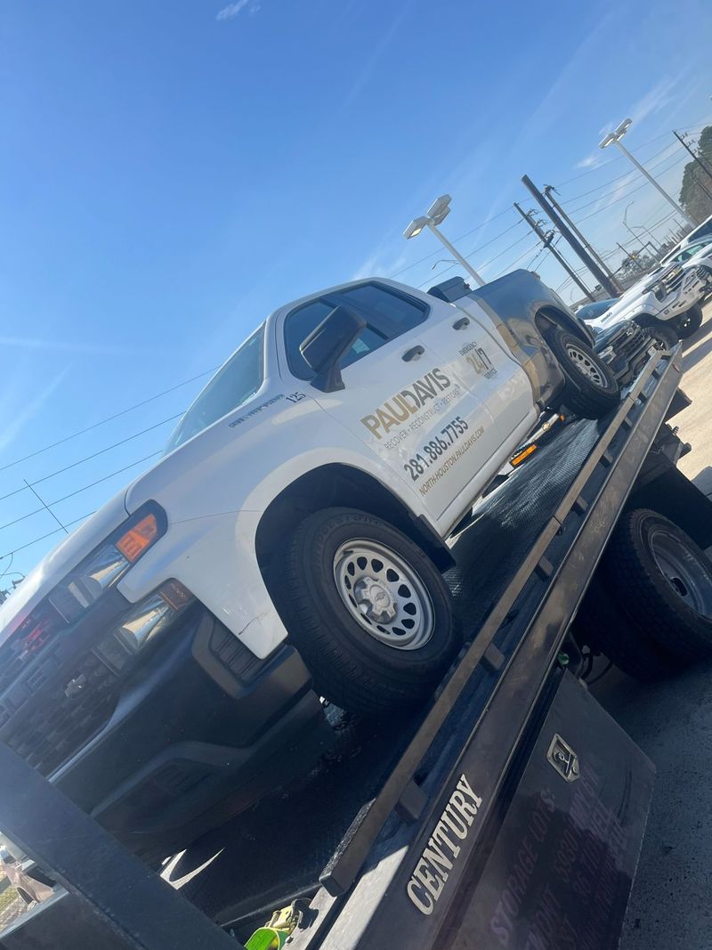 A flatbed tow truck carrying a vehicle in Houston, showcasing Turbo Tows' roadside assistance services.