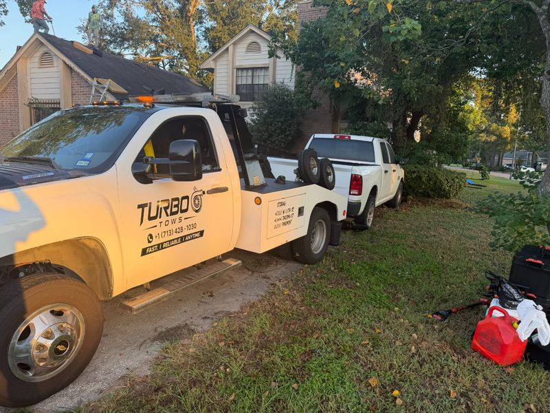 Turbo Tows towing vehicle parked with a white truck nearby in Houston, showcasing roadside assistance service.